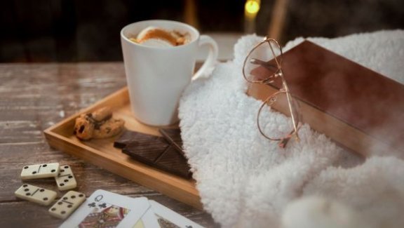 indoor activities for cold weather, cozy image with hot cocoa, a book, and cards