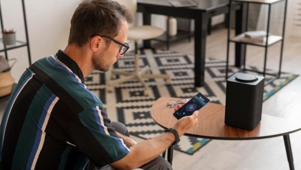 fiber internet vs fixed wireless, man holding phone next to speaker